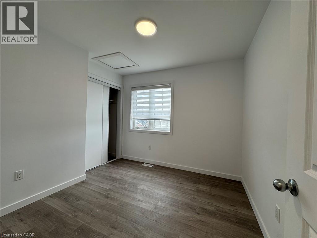 Room featuring wood-finish flooring, a window with horizontal blinds, a ceiling-mounted light fixture, and a closet with sliding doors - 119 Highriver Trail Unit# Main, Welland, ON - Indoor Photo Showing Other Room