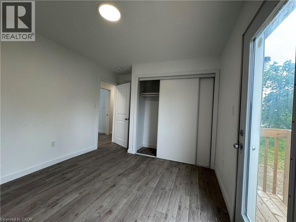 Room featuring wood-finish flooring, recessed lighting, white walls, a sliding glass door to an exterior deck, and a closet with sliding panel doors - 119 Highriver Trail Unit# Main, Welland, ON - Indoor Photo Showing Other Room