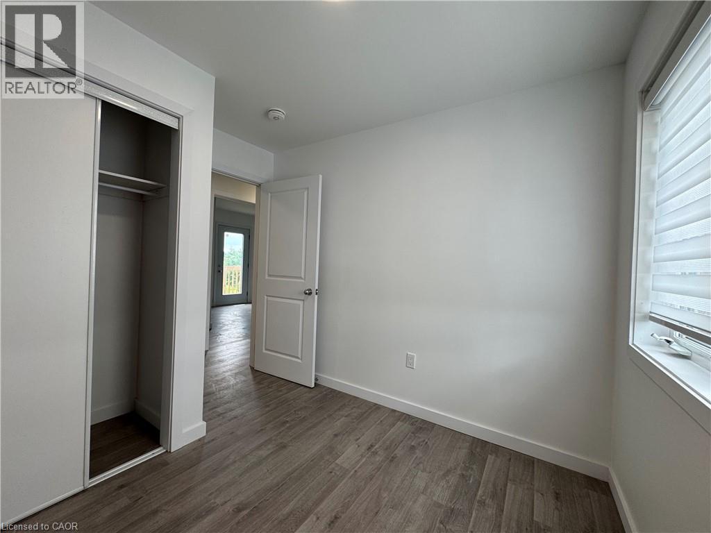 Interior room featuring wood-finish flooring, white walls, and a window with horizontal blinds - 119 Highriver Trail Unit# Main, Welland, ON - Indoor Photo Showing Other Room
