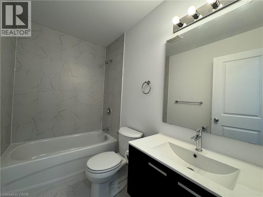 Bathroom featuring a modern vanity with integrated sink, chrome faucet, and rectangular mirror - 119 Highriver Trail Unit# Main, Welland, ON - Indoor Photo Showing Bathroom