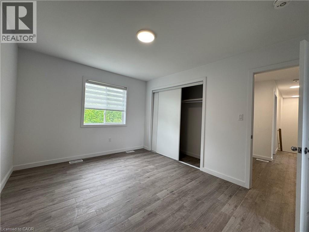 Bright interior room featuring wood-finish flooring, a window with horizontal blinds, and a built-in closet with sliding doors - 119 Highriver Trail Unit# Main, Welland, ON - Indoor Photo Showing Other Room