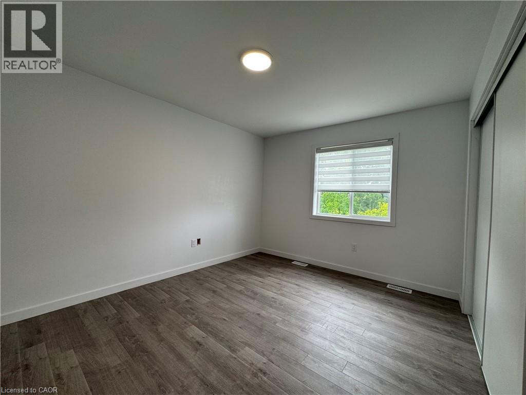 Bright room featuring wood-finish flooring, white walls, and a window with blinds - 119 Highriver Trail Unit# Main, Welland, ON - Indoor Photo Showing Other Room