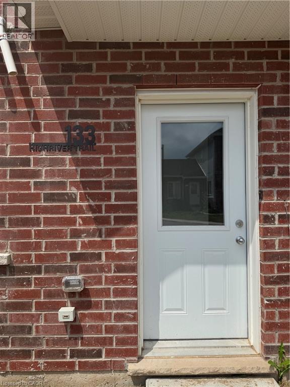 Red brick exterior featuring a white paneled door with an upper glass insert - 133 Highriver Trail Unit# Main, Welland, ON