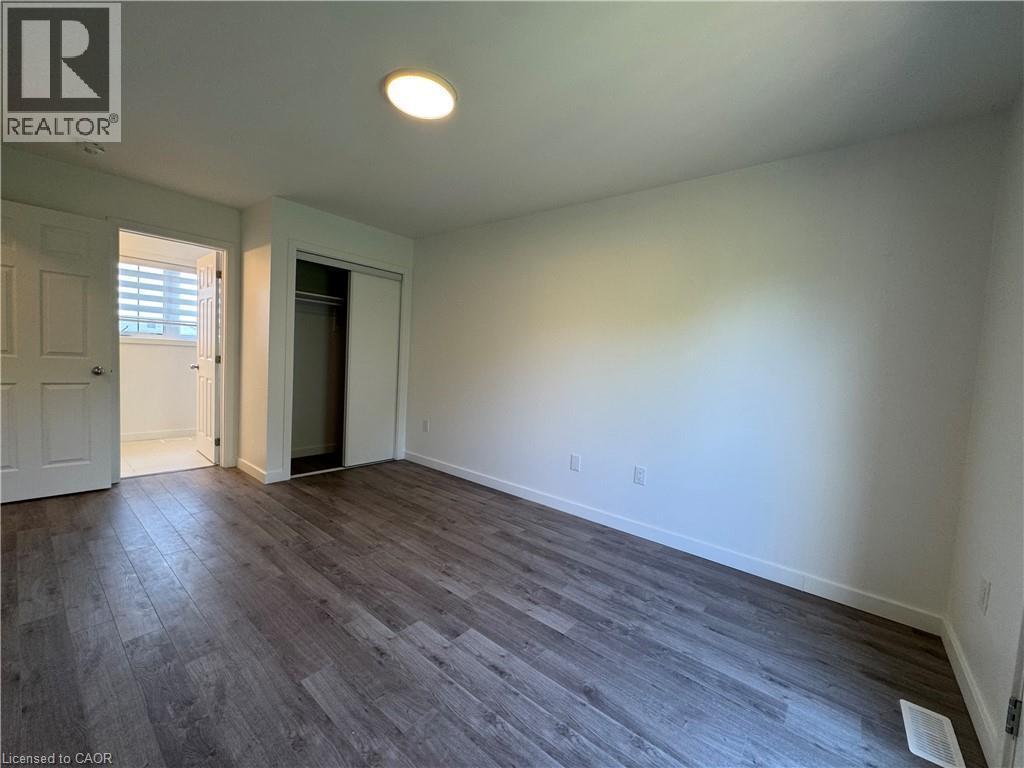 Spacious interior room featuring wood-finish flooring, recessed ceiling lighting, and crisp white walls - 133 Highriver Trail Unit# Main, Welland, ON