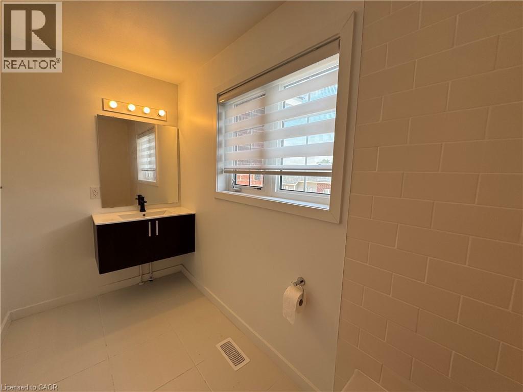 Modern bathroom featuring a floating vanity with a white countertop and dark wood-finish cabinetry - 133 Highriver Trail Unit# Main, Welland, ON