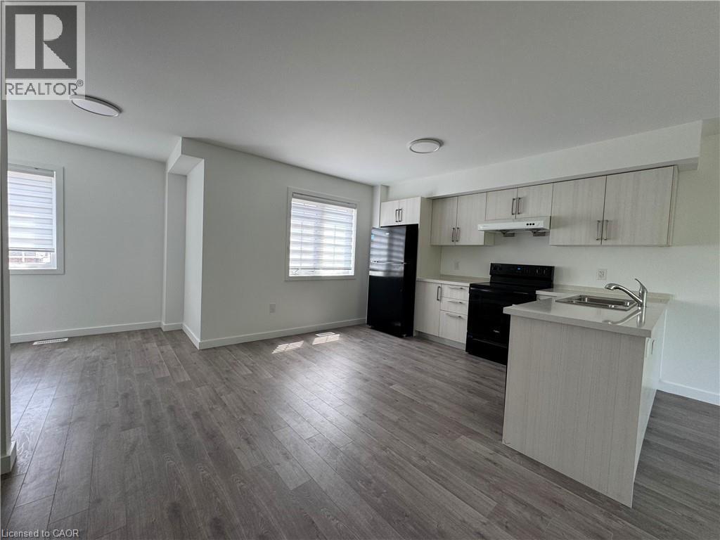 Modern kitchen with light wood-finish cabinetry, black appliances, and a peninsula with a stainless steel sink - 133 Highriver Trail Unit# Main, Welland, ON
