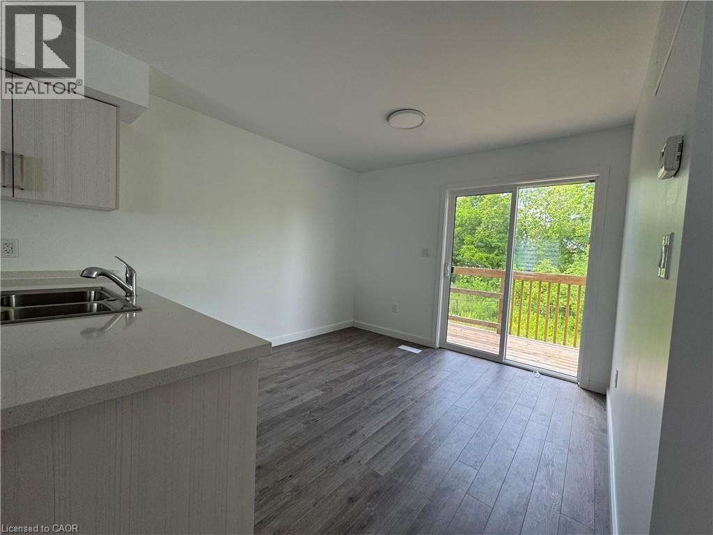 Contemporary kitchen area featuring a stainless steel double sink, light grey countertop, and light wood-grain cabinetry - 133 Highriver Trail Unit# Main, Welland, ON