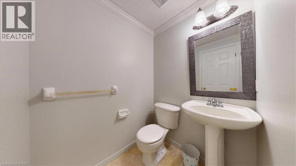 Pedestal sink with chrome fixtures, framed mirror, two-bulb vanity light, and a toilet - 980 Creekside Drive, Waterloo, ON - Indoor Photo Showing Bathroom