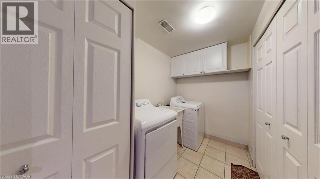 Dedicated laundry area featuring tile flooring, white shaker-style cabinetry, and an overhead light fixture - 980 Creekside Drive, Waterloo, ON - Indoor Photo Showing Laundry Room