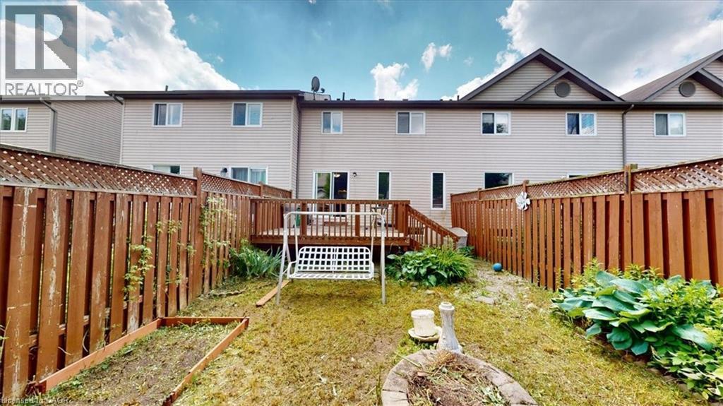 Private backyard featuring a wooden deck with railing, surrounded by a tall wood privacy fence - 980 Creekside Drive, Waterloo, ON - Outdoor With Deck Patio Veranda With Exterior