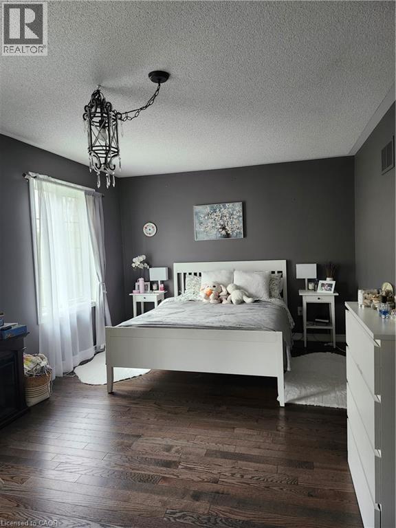 Spacious room featuring dark wood-finish flooring, dark grey wall tones, and crown molding - 249 Bussel Crescent, Milton, ON