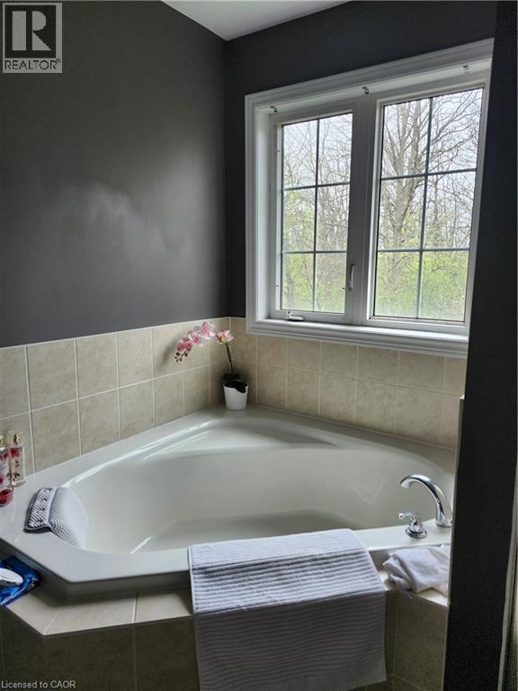 Corner soaking tub with tiled surround, chrome fixtures, and a multi-pane window - 249 Bussel Crescent, Milton, ON