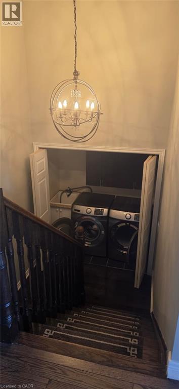 Convenient laundry area featuring a utility sink, dark wood-finish flooring, and bi-fold closet doors, illuminated by an overhead chandelier - 249 Bussel Crescent, Milton, ON