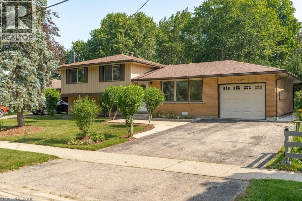 Split-level residence featuring a brick and siding exterior, an attached garage, and a paved driveway - 64 Warren Road, Kitchener, ON