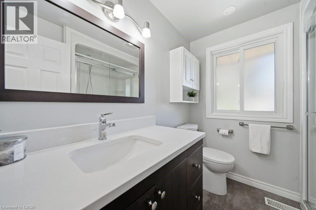 Contemporary bathroom featuring a dark wood-finish vanity with a white countertop and integrated sink - 64 Warren Road, Kitchener, ON
