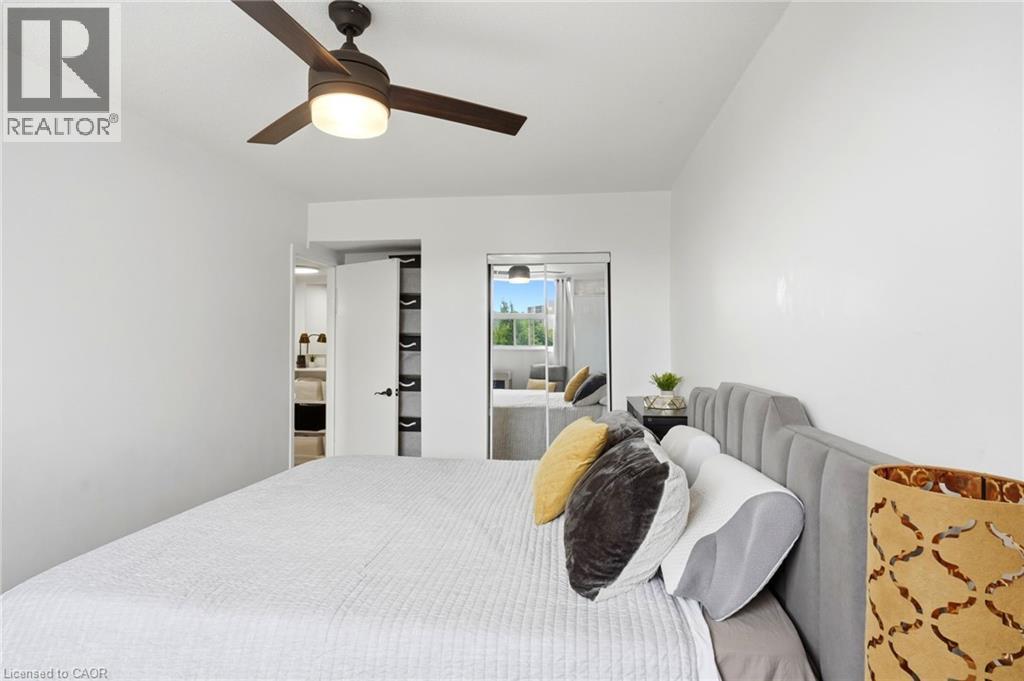 Bedroom featuring a ceiling fan with integrated lighting, white walls, and wood-finish flooring - 15 Nicklaus Drive Unit# 17, Hamilton, ON