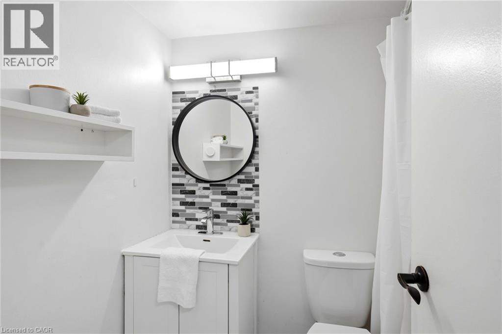 Contemporary vanity featuring an integrated sink, polished chrome faucet, and a mosaic tile backsplash - 15 Nicklaus Drive Unit# 17, Hamilton, ON