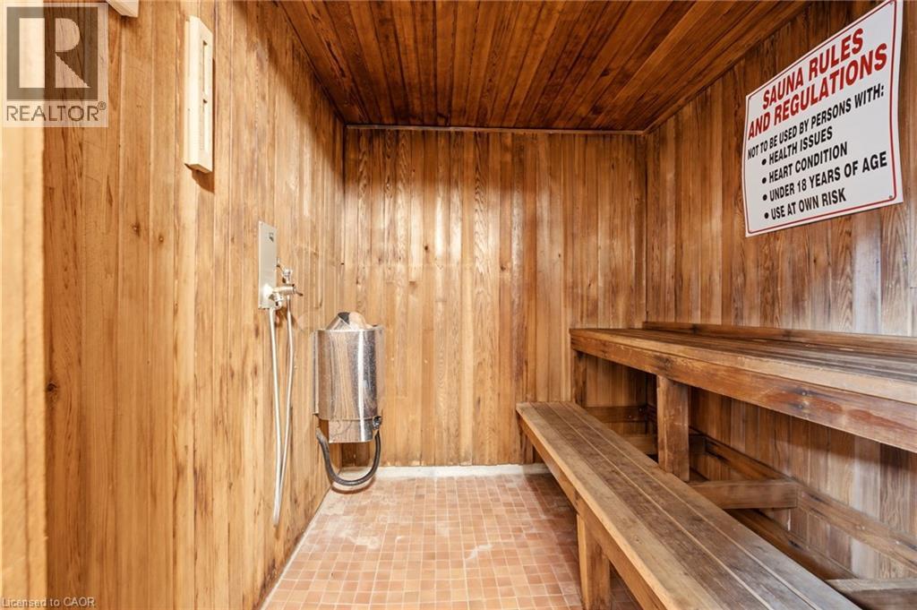 Wood-paneled sauna featuring tiered wood benches, a wall-mounted heater, and tiled flooring - 15 Nicklaus Drive Unit# 17, Hamilton, ON