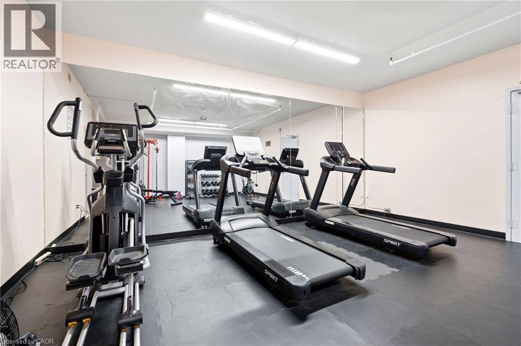 Dedicated fitness room featuring wall-to-wall mirrors, durable rubber flooring, and bright overhead strip lighting - 15 Nicklaus Drive Unit# 17, Hamilton, ON