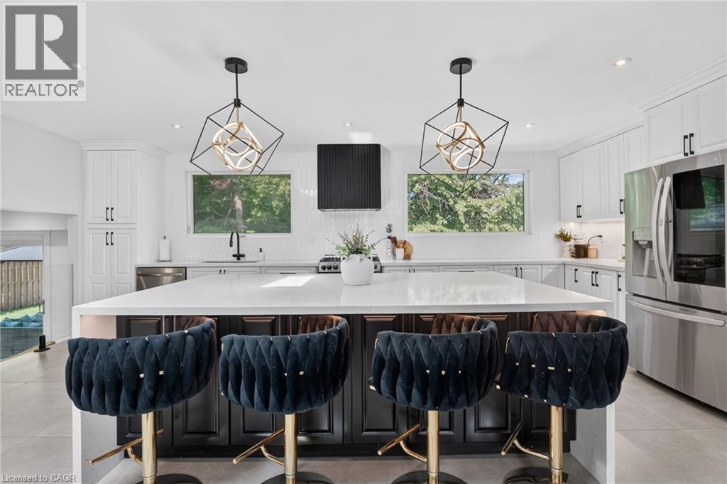 Spacious kitchen island with a light-toned countertop, complemented by a stainless steel refrigerator and dishwasher - 9 Leslie Drive, Hamilton, ON - Indoor