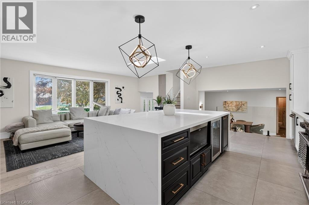 Kitchen island with quartz waterfall countertop, dark cabinetry, and gold-tone hardware - 9 Leslie Drive, Hamilton, ON - Indoor