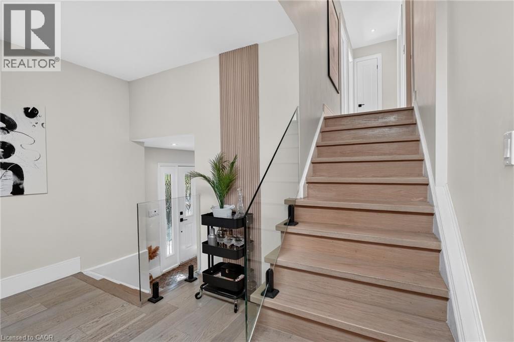 Light wood-finish staircase with clear glass railing - 9 Leslie Drive, Hamilton, ON - Indoor Photo Showing Other Room