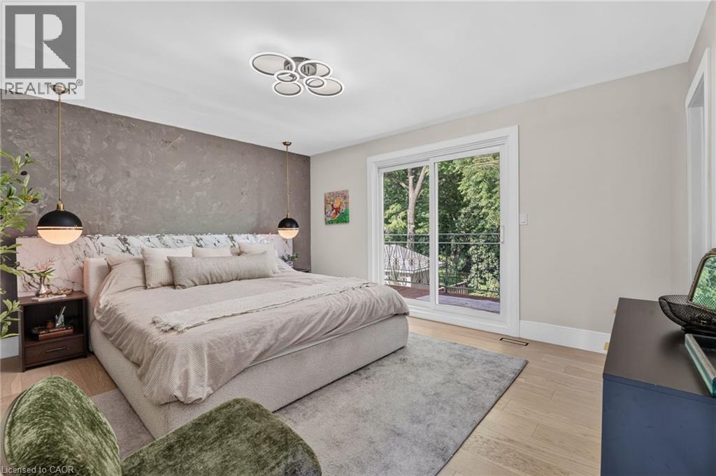 Spacious bedroom featuring light wood-finish flooring, a textured accent wall, and a contemporary ceiling light fixture - 9 Leslie Drive, Hamilton, ON - Indoor Photo Showing Bedroom