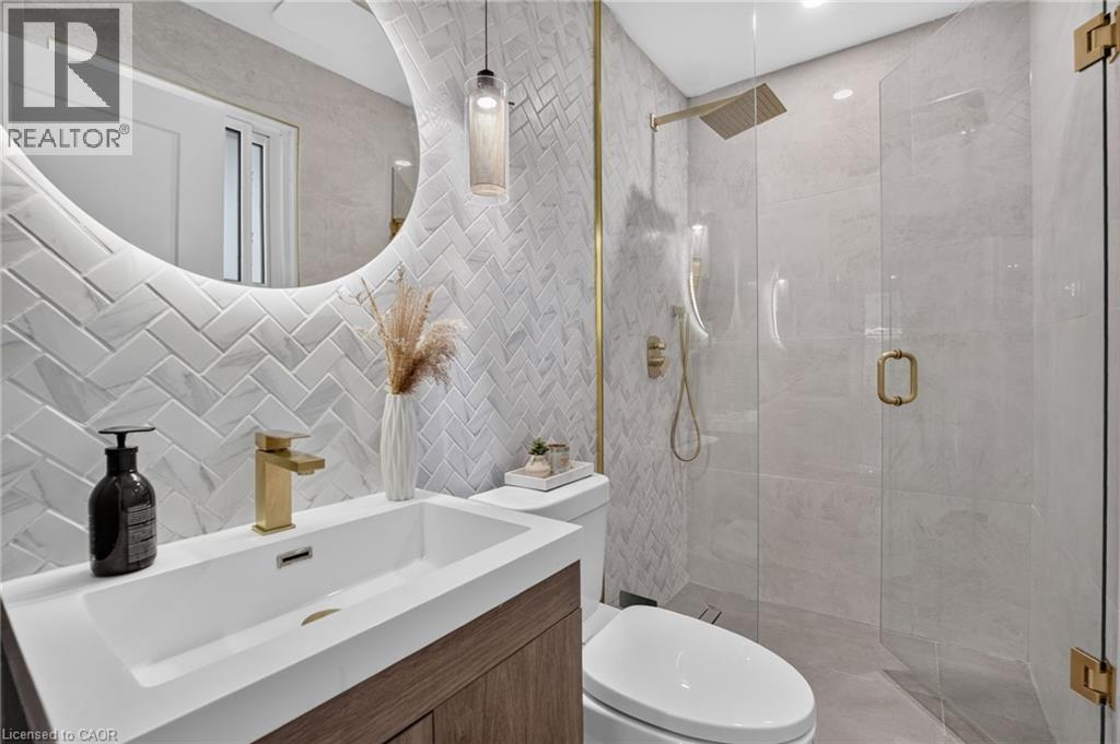 Contemporary bathroom featuring a floating wood-finish vanity with an integrated rectangular sink and gold-tone faucet - 9 Leslie Drive, Hamilton, ON - Indoor Photo Showing Bathroom