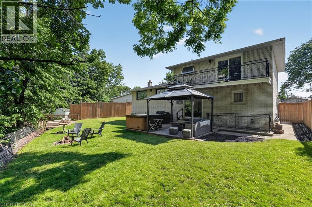 Spacious rear yard featuring an expansive lawn, established trees, and wood fencing - 9 Leslie Drive, Hamilton, ON - Outdoor With Balcony