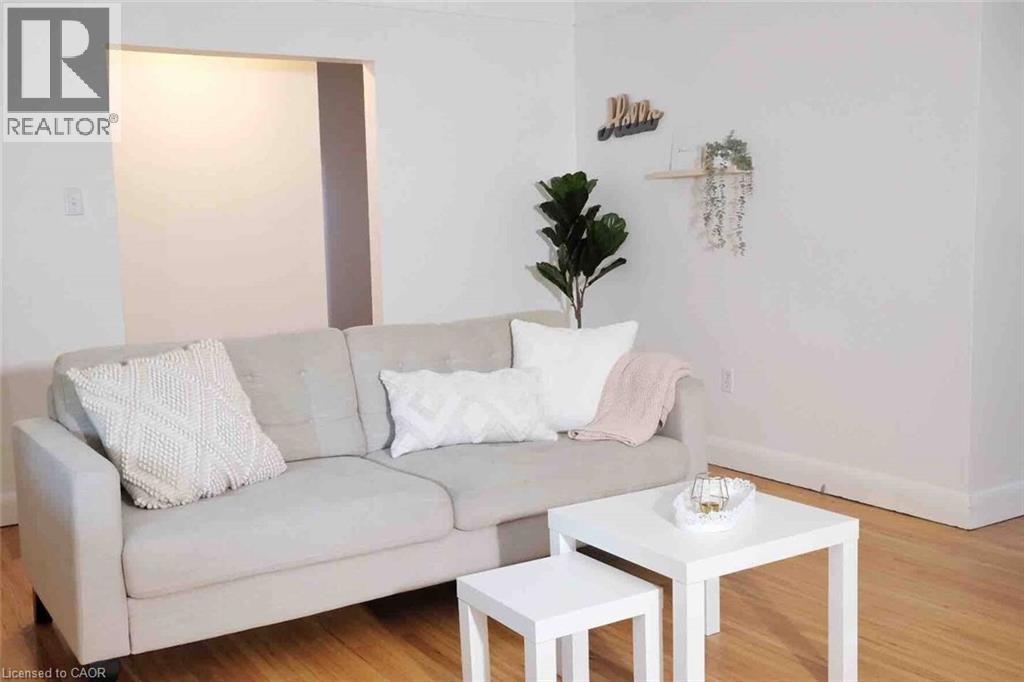 Bright living space featuring warm wood-finish flooring, crisp white walls, and a recessed wall opening - 919 Montgomery Drive, Ancaster, ON