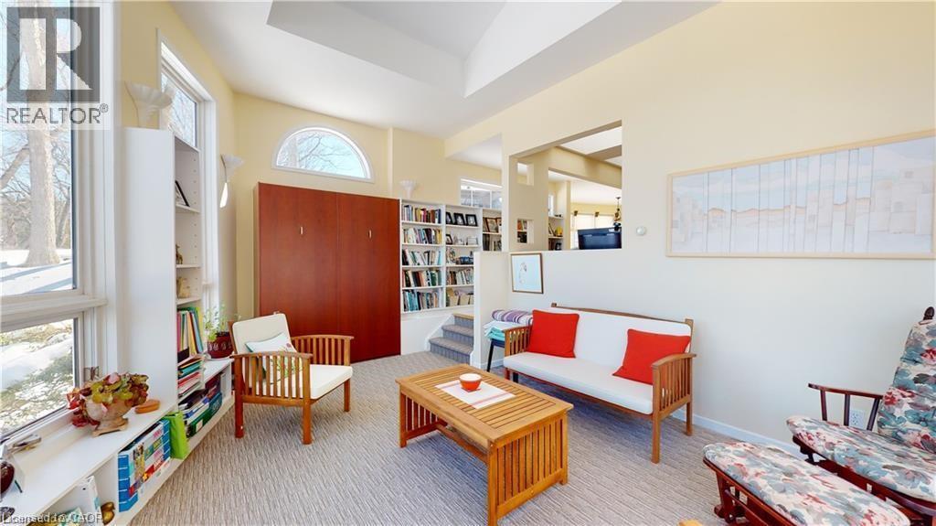 Living area featuring vaulted ceilings, built-in shelving, large windows with exterior views, a built-in wall unit, and a pass-through opening to an additional space - 919 Montgomery Drive, Ancaster, ON