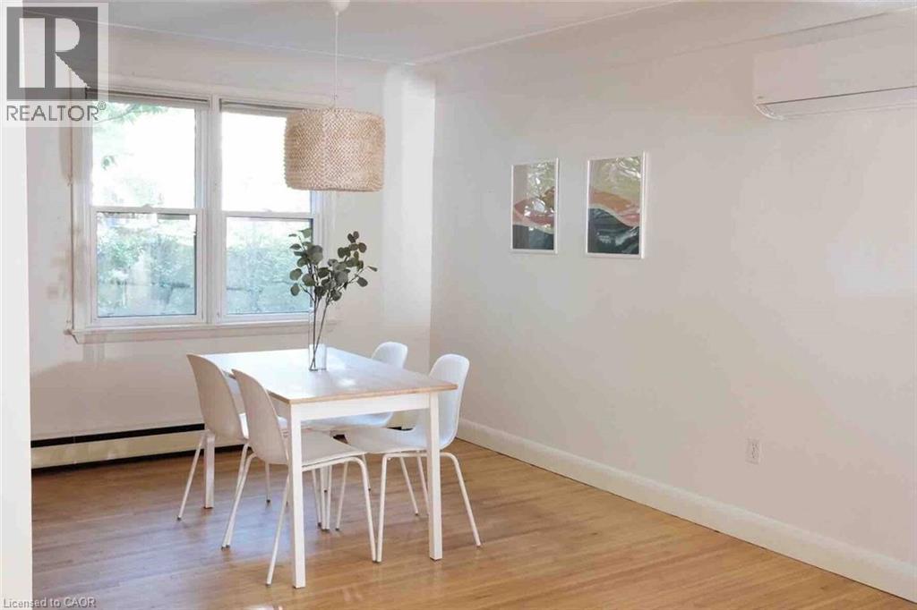 Spacious room featuring wood-finish flooring, white baseboards, and a window with white trim - 919 Montgomery Drive, Ancaster, ON