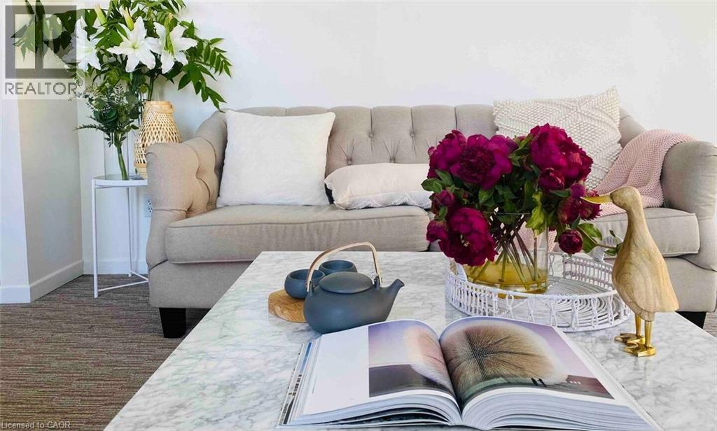 Bright living area with neutral wall tones and textured carpet flooring - 919 Montgomery Drive, Ancaster, ON