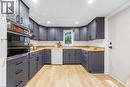 Kitchen featuring dark gray cabinetry, natural wood-finish countertops, and light wood-finish flooring - 11 Ford Street, Hamilton, ON 