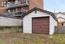 Detached single-car garage featuring a brown sectional door and white siding - 11 Ford Street, Hamilton, ON 