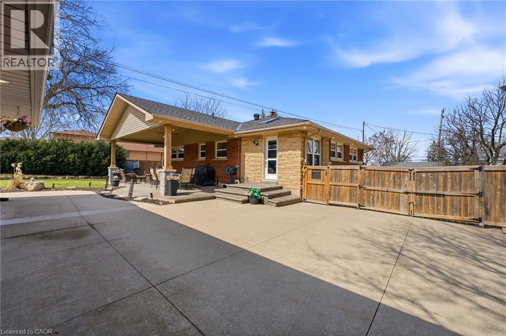 Rear view of property with a patio area, a gate, and brick siding - 473 Mohawk Road W, Hamilton, ON