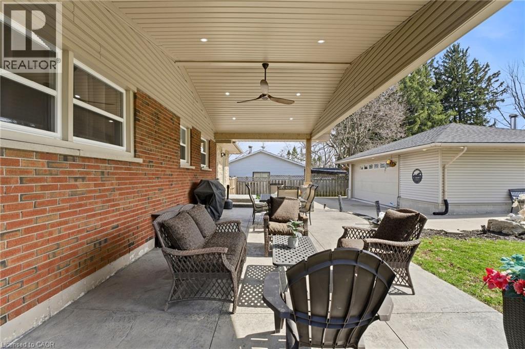 View of patio with outdoor seating, ceiling fan, area for grilling, an outdoor structure, and a garage - 473 Mohawk Road W, Hamilton, ON