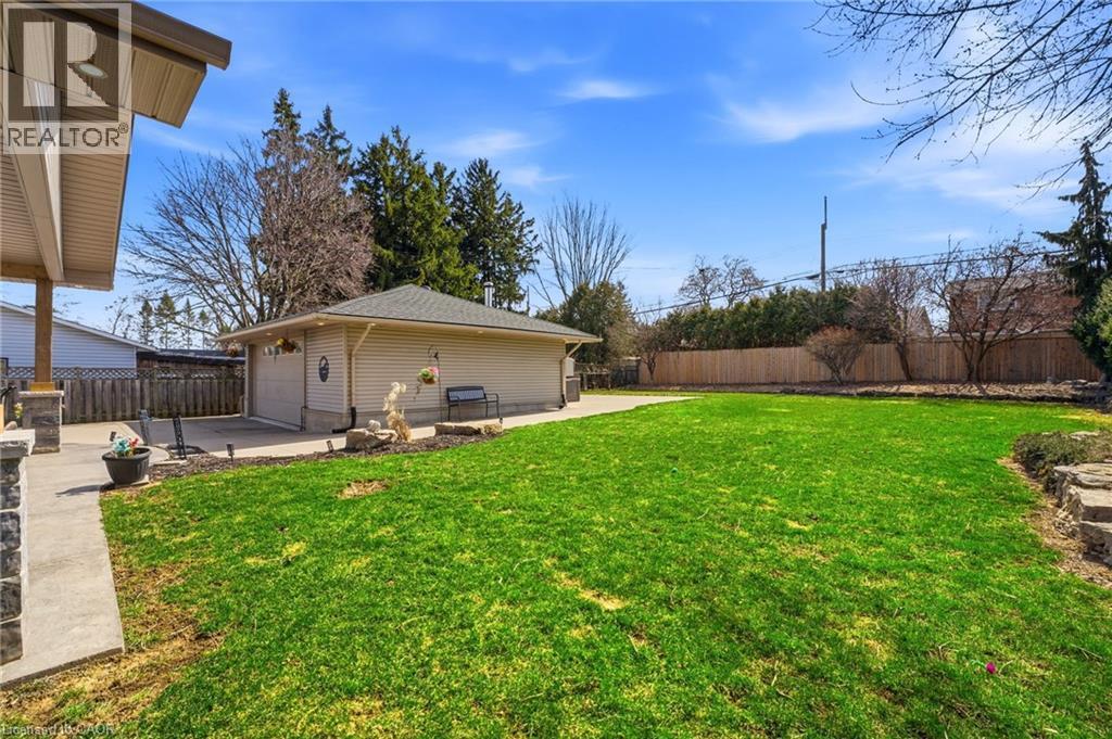 Fenced backyard with a patio area, a detached garage, and an outbuilding - 473 Mohawk Road W, Hamilton, ON