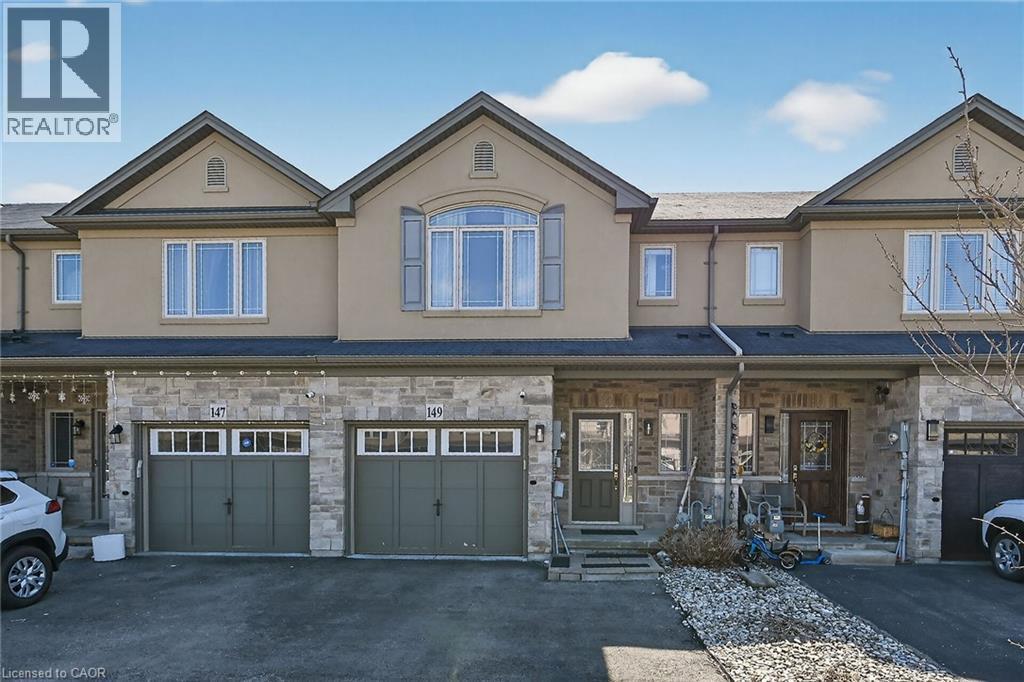 Townhome exterior featuring a stucco and stone facade with multiple gables - 149 Kinsman Drive, Binbrook, ON