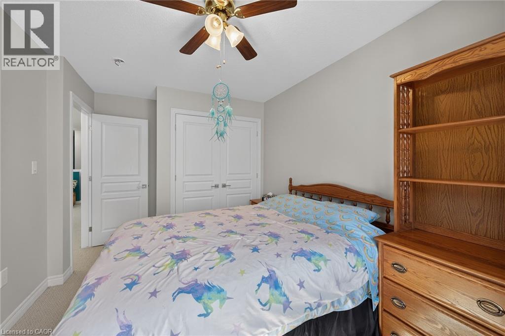 Carpeted room featuring a ceiling fan with integrated lighting, a paneled door, and a bi-fold closet door - 149 Kinsman Drive, Binbrook, ON