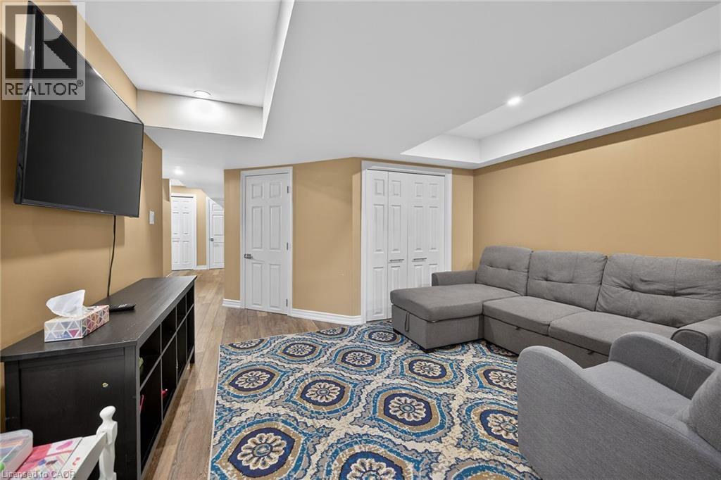 Recreation room featuring recessed lighting, wood-finish flooring, warm-toned walls, and multiple white paneled doors - 149 Kinsman Drive, Binbrook, ON