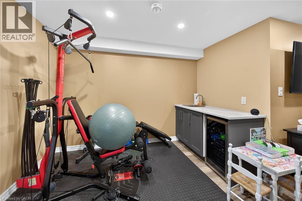 Dedicated fitness area featuring durable rubber flooring, recessed lighting, and a built-in wet bar with a compact beverage cooler - 149 Kinsman Drive, Binbrook, ON