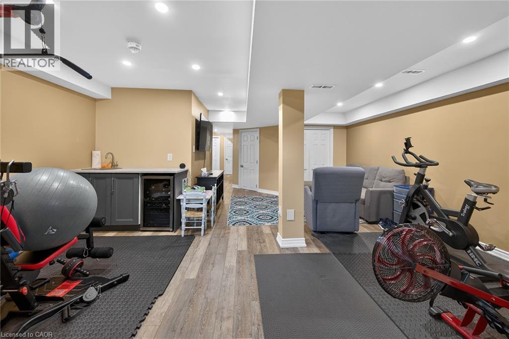 Finished lower level featuring recessed lighting, wood-finish flooring, a built-in wet bar with sink, and integrated beverage refrigeration - 149 Kinsman Drive, Binbrook, ON