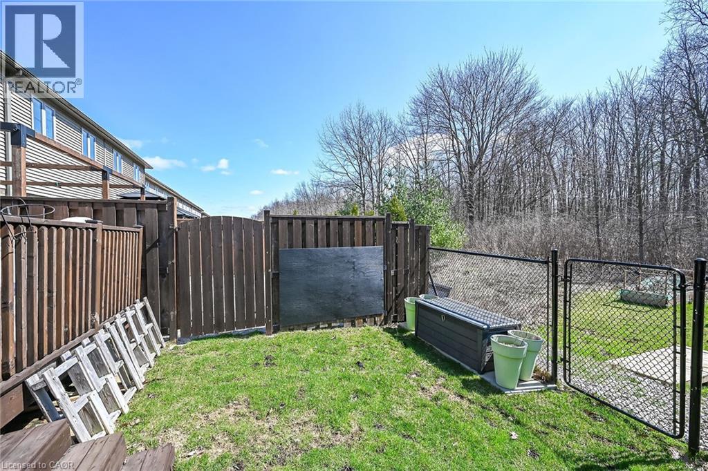 Grassed backyard area featuring a wood privacy fence, chain link fence, and a natural wooded backdrop - 149 Kinsman Drive, Binbrook, ON