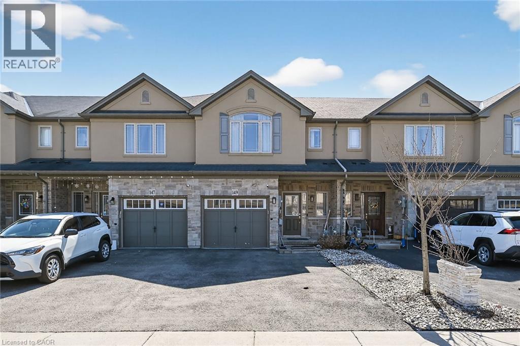 Townhome exterior featuring stone and stucco finishes, multiple dormers, and individual garages - 149 Kinsman Drive, Binbrook, ON