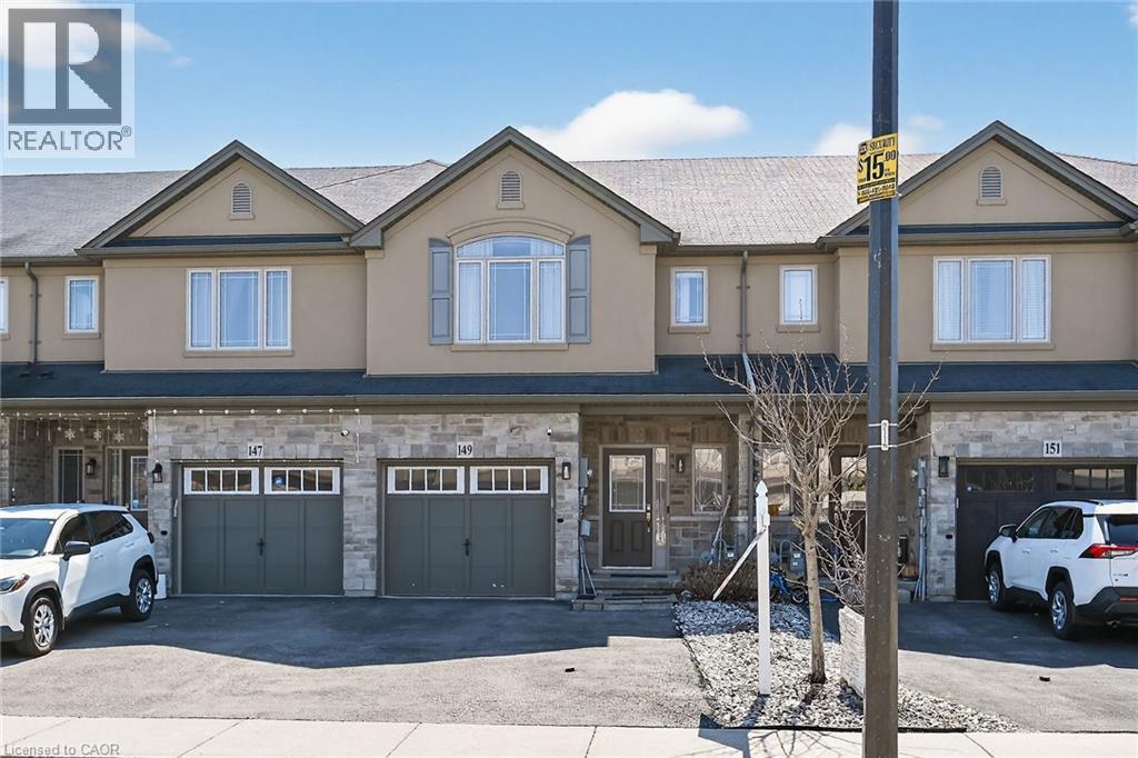 Townhome exterior featuring a stone and stucco facade, an attached garage, and a paved driveway - 149 Kinsman Drive, Binbrook, ON