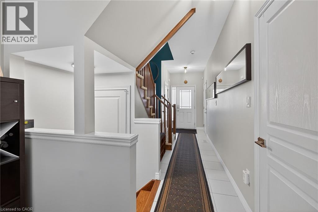 Entryway featuring a white paneled door with frosted glass insert, white tile flooring, and a stairway with wood handrails and risers - 149 Kinsman Drive, Binbrook, ON