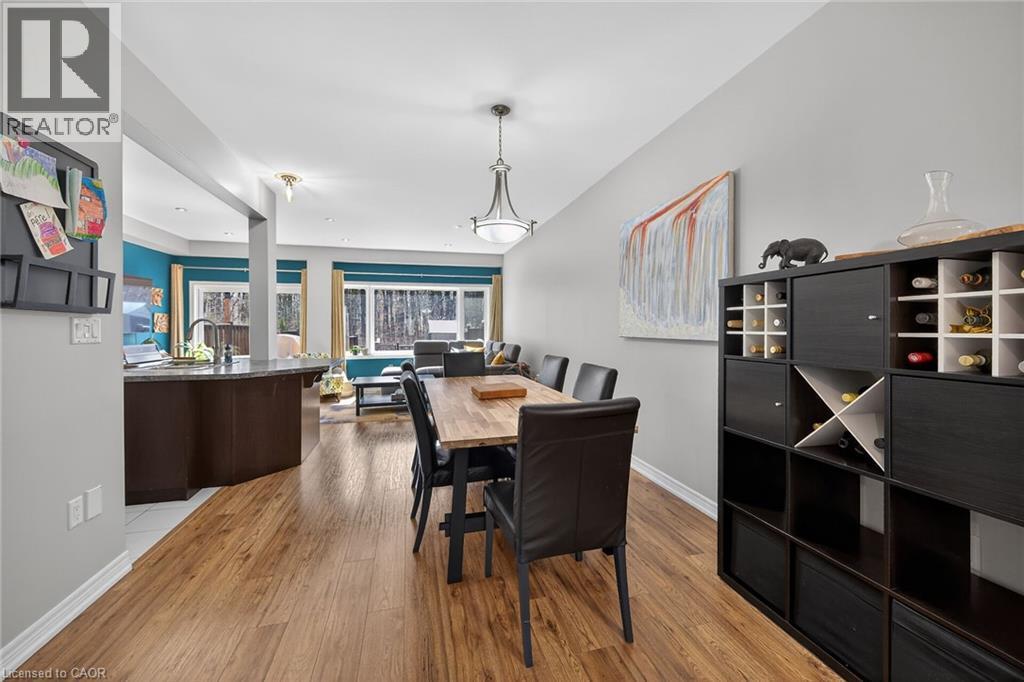 Open-concept dining area featuring wood-finish flooring, a contemporary chandelier, and a built-in shelving unit - 149 Kinsman Drive, Binbrook, ON