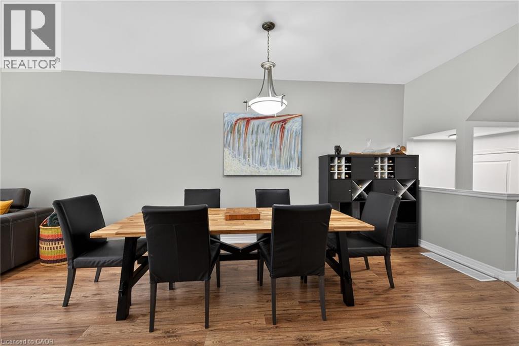 Dining area featuring wood-finish flooring, a contemporary ceiling pendant light fixture, and a built-in storage unit with wine bottle cubbies - 149 Kinsman Drive, Binbrook, ON