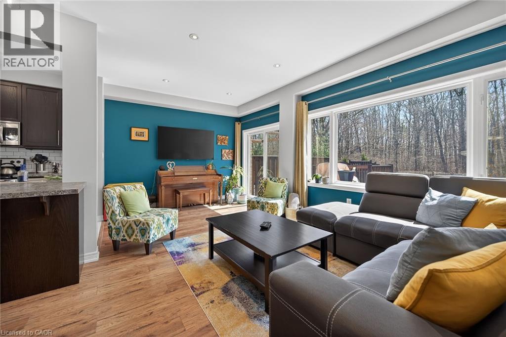 Bright living area featuring large windows, wood-finish flooring, recessed lighting, a sliding glass door, and an open concept layout with a kitchen pass-through - 149 Kinsman Drive, Binbrook, ON